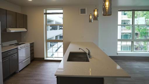 A modern kitchen with a large island and a view of the outside at Denver Metro Village Apartments, Denver, CO, 80204