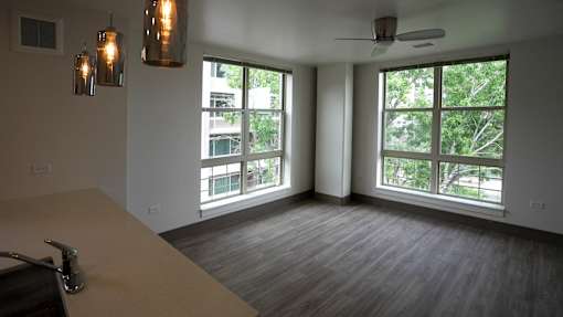 A room with a table, chairs, and a window overlooking a tree-filled area at Denver Metro Village Apartments, Denver, CO