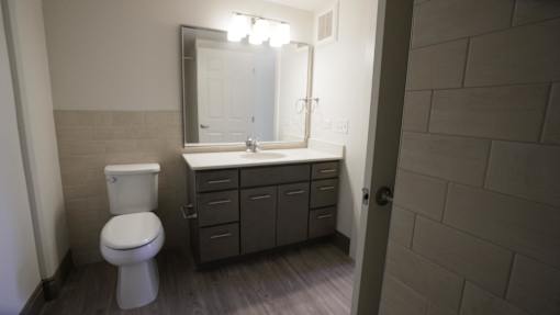 A bathroom with a toilet, sink, and mirror at Denver Metro Village Apartments, Denver, CO, 80204