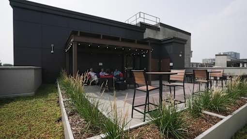 A modern outdoor seating area with a bar and people sitting at tables at Denver Metro Village Apartments, Denver, 80204