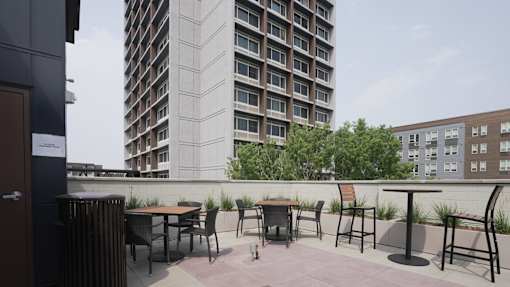 A patio with a table and chairs overlooks a tall building at Denver Metro Village Apartments, Denver, Colorado