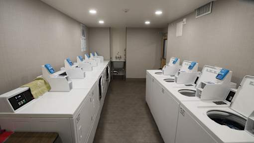 A laundromat with rows of washers and dryers at Denver Metro Village Apartments, Colorado