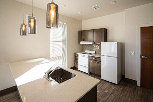 A kitchen with a sink, stove, and refrigerator at Denver Metro Village Apartments, Denver