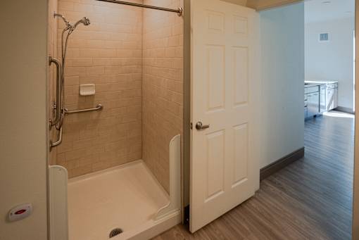 A bathroom with a walk in shower and a white door at Denver Metro Village Apartments, Colorado, 80204