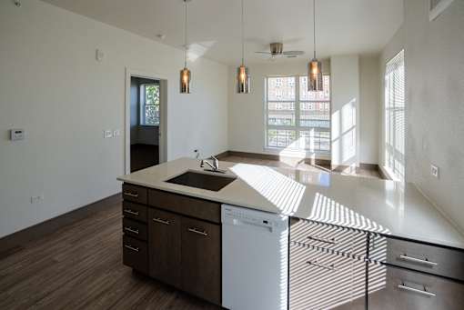A modern kitchen with a white countertop and wooden cabinets at Denver Metro Village Apartments, Denver, Colorado
