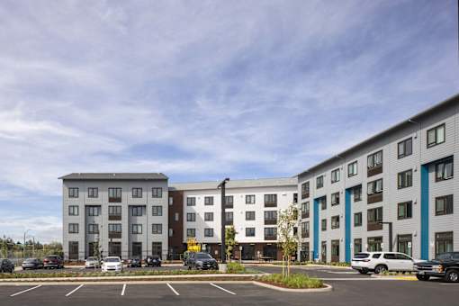 A parking lot in front of a multi-story apartment building.