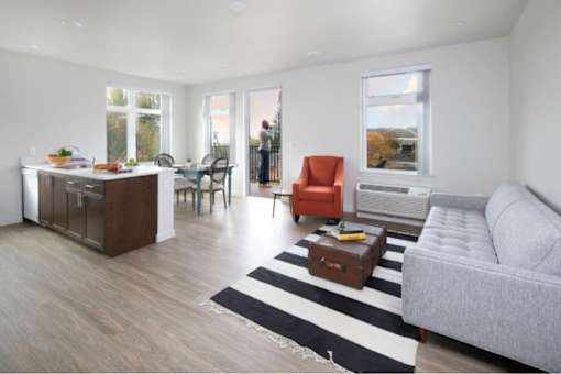 A living room with a grey couch, a brown cabinet, and a striped rug.