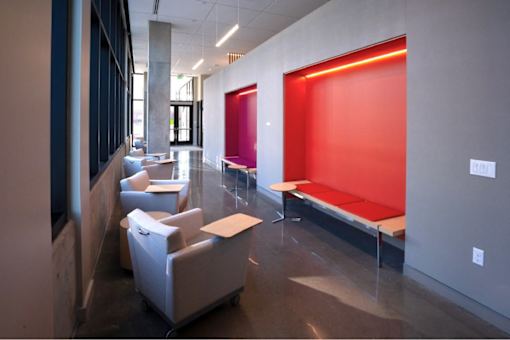 A brightly lit waiting area with a red wall and white furniture.