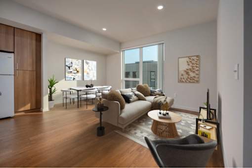 A modern living room with a grey sofa, a wooden coffee table, and a grey armchair.