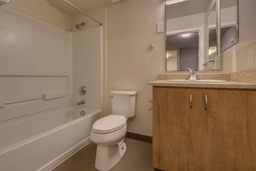 A white toilet sits in a bathroom next to a bathtub and a sink.