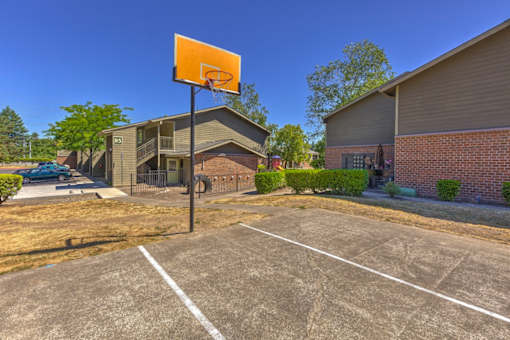 A basketball hoop stands in the middle of a parking lot.