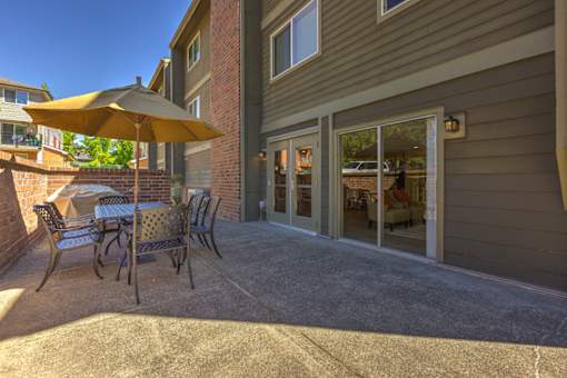 A patio with a table and chairs and an umbrella.