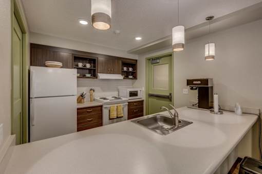 A modern kitchen with a white countertop and stainless steel sink.