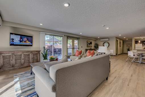 A modern living room with a large couch and a television mounted on the wall.