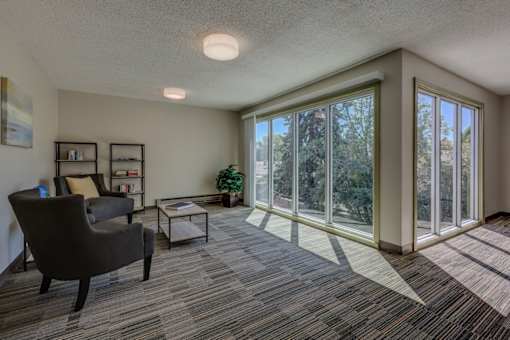 A living room with a grey carpet and a large window.