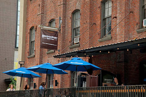 A group of people are sitting at an outdoor table under blue umbrellas.