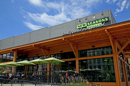 A restaurant named New Seasons with a wooden facade and green umbrellas.
