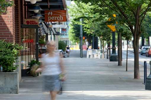 A blurry image of a woman walking on a sidewalk.