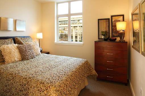 A bedroom with a bed, dresser, and window.