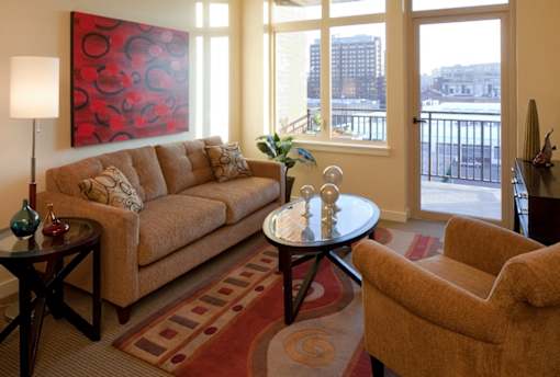 A living room with a couch, a chair, a table, and a painting on the wall.