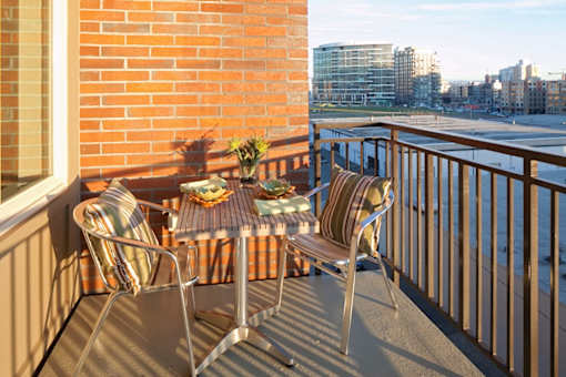 A balcony with a table and chairs overlooking a cityscape.