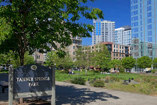 A sign that says Tanner Springs Park in front of a city park.