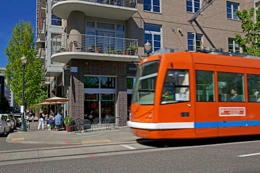 An orange tram is on a city street.