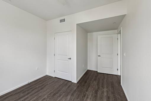 A room with two white doors and a wooden floor.