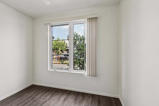 A room with a window showing a view of a street with cars and trees.