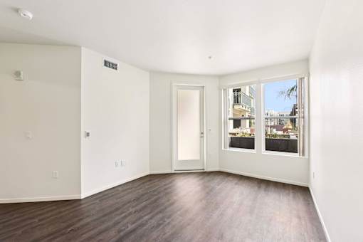 A room with a door and a window with a view of a building outside.