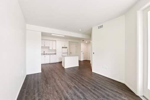 A large empty room with wood flooring and white walls.