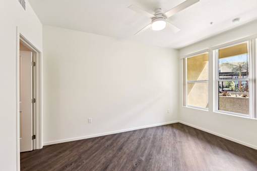 A room with a ceiling fan and a window overlooking a backyard.
