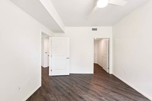 A room with white walls and wood flooring with two doors.