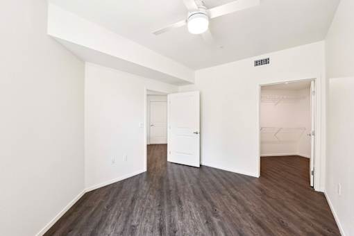 A room with a ceiling fan and wood flooring.
