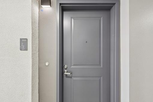 A grey door with a silver handle and a number 3100 on the wall.