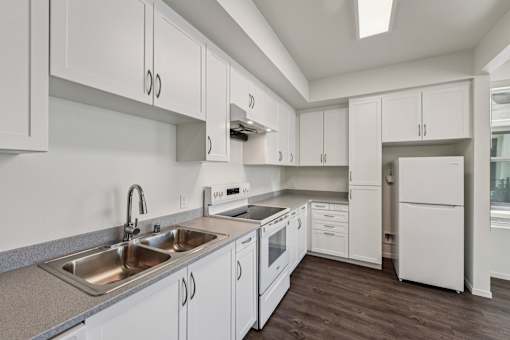 A kitchen with white cabinets and a stainless steel sink.