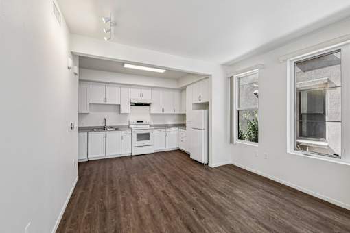 A kitchen with white cabinets and a wooden floor.