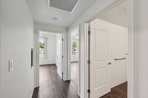 A hallway with white doors and a window.