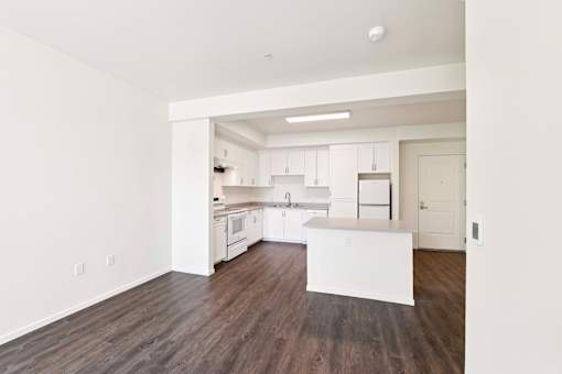 A kitchen with white cabinets and a wooden floor.