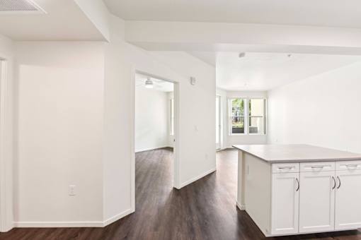 A kitchen with white cabinets and a wooden floor.