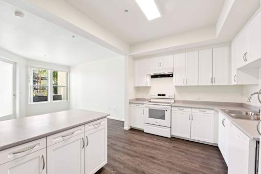 A kitchen with white cabinets and a stove top oven.