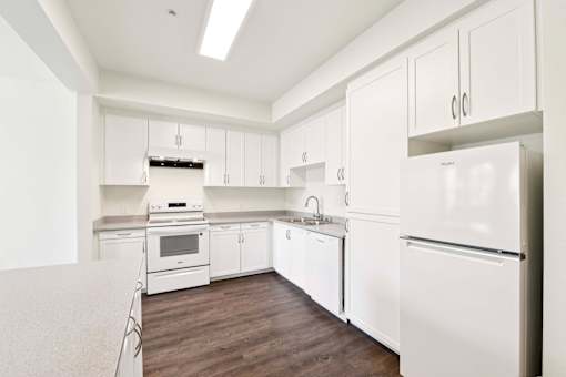 A white kitchen with a refrigerator on the right.