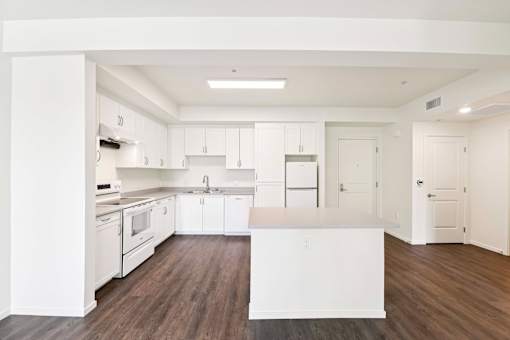 A kitchen with white cabinets and a wooden floor.