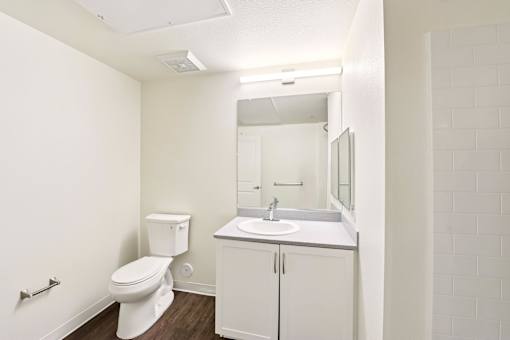 A white bathroom with a toilet, sink, and mirror.