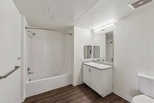 A white bathroom with a tub, sink, and mirror.
