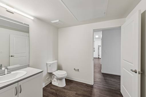 A white bathroom with a toilet, sink, and mirror.