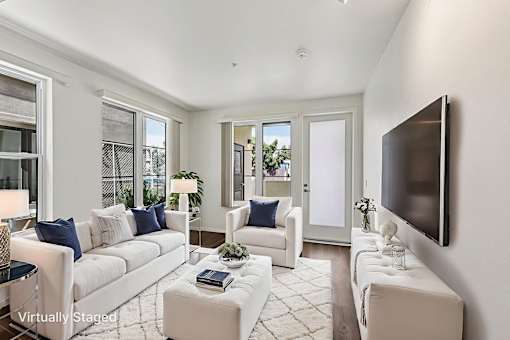 A living room with white furniture and a flat screen TV mounted on the wall.