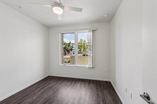 A room with a window and a fan on the ceiling.