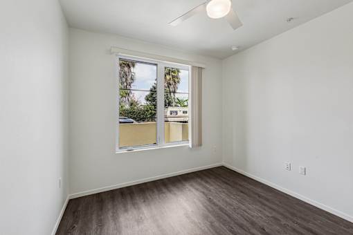 A room with a window and a fan on the ceiling.