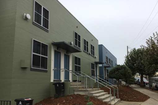 A grey building with a blue door and steps leading up to it.